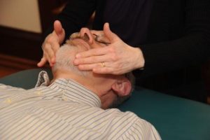 A person is doing reiki on another person 's face.